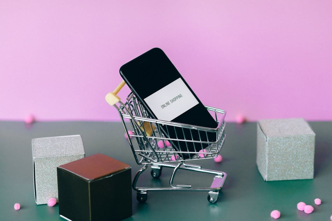 A smartphone with a shopping cart depicting the concept of online shopping in a colorful studio setup.